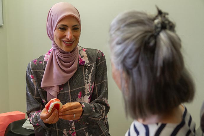 Dr. Iman Ayoubi shows a dental impression to an older female patient