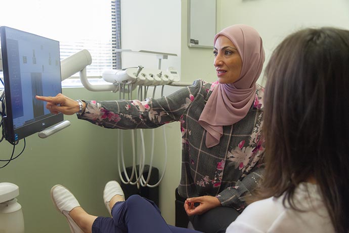 Dr. Iman Ayoubi points at an image in the computer monitor for her patient to see