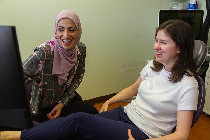 Dr. Iman Ayoubi and a female patient have a laugh as they look on at the computer monitor