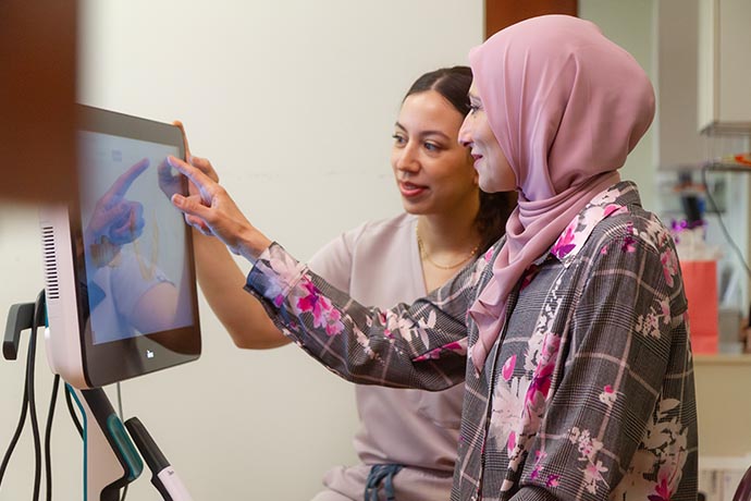 Dr. Iman Ayoubi points to the computer monitor as a female staff looks on