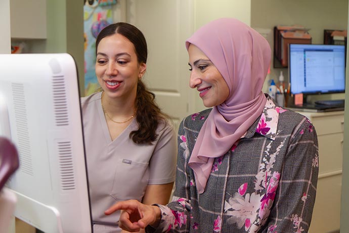 Dr. Iman Ayoubi sits with a female staff and looking at the monitor
