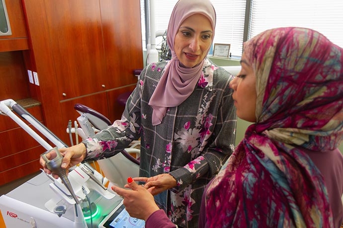 Dr. Iman Ayoubi shows the tools to a female dental staff inside the lab of Allure Dental